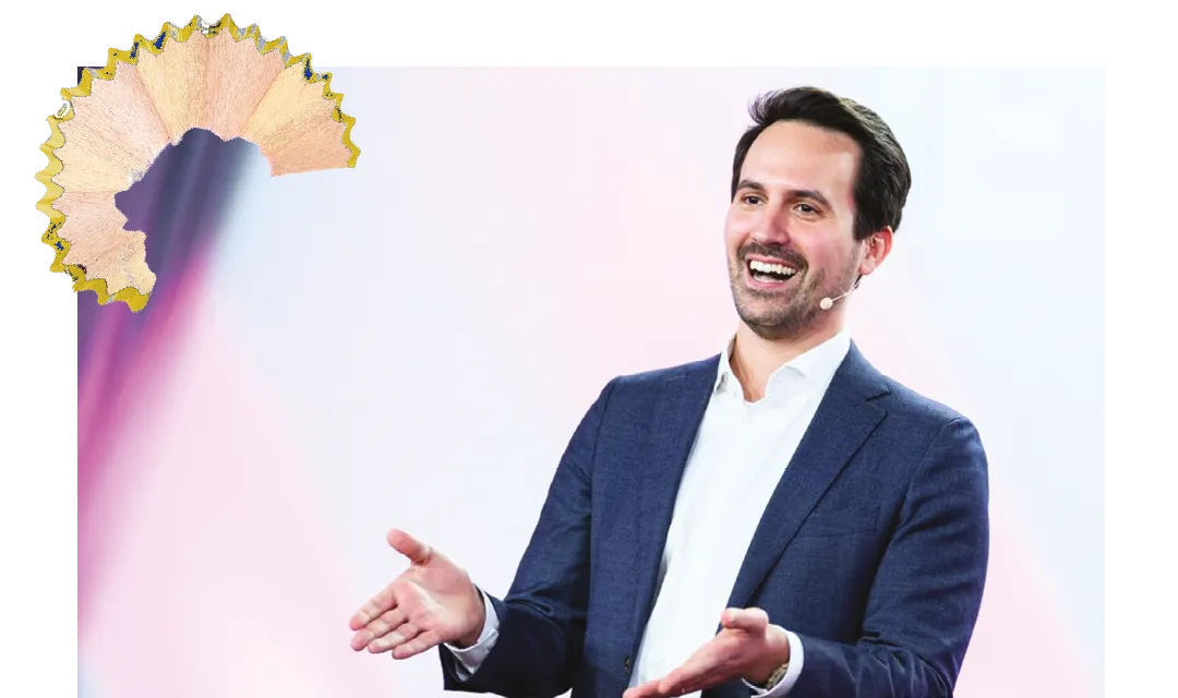 Christoph Wiederkehr lächelt und gestikuliert während eines Vortrags oder einer Präsentation vor neutralem Hintergrund.