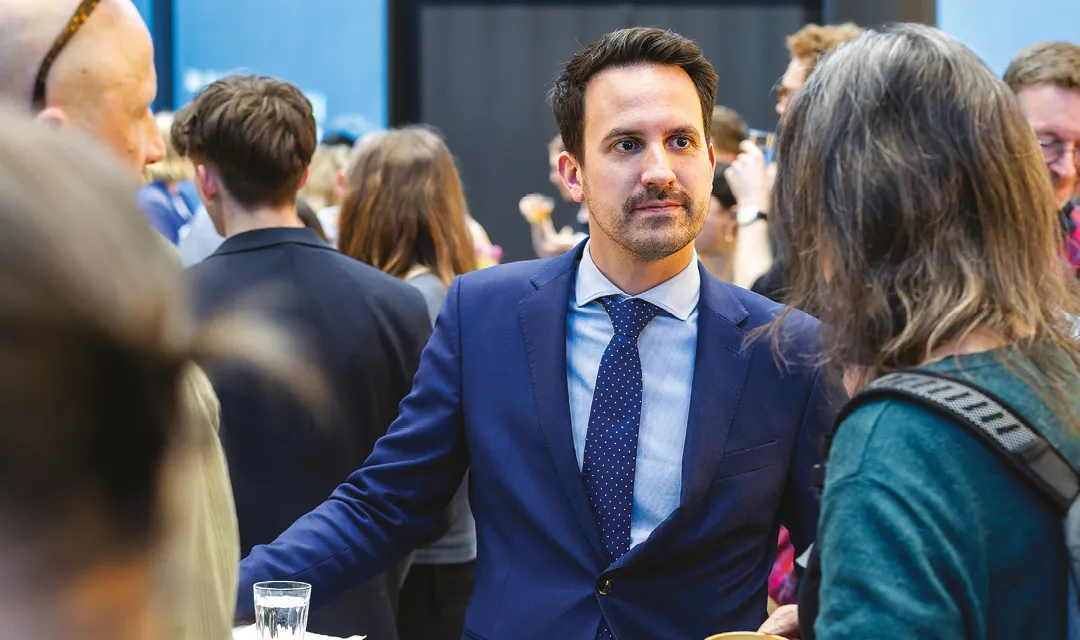 Christoph Wiederkehr unterhält sich inmitten einer größeren Menschenmenge mit einer Teilnehmerin bei einer Veranstaltung.